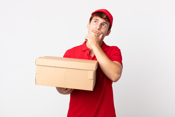 Wall Mural - young handsome man thinking, feeling doubtful and confused delivery package service concept.