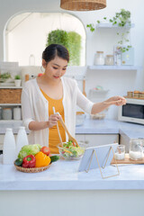 Wall Mural - Beautiful young woman with tablet computer cooking in kitchen