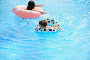 Happy child and woman playing in swimming pool. Summer vacation concept