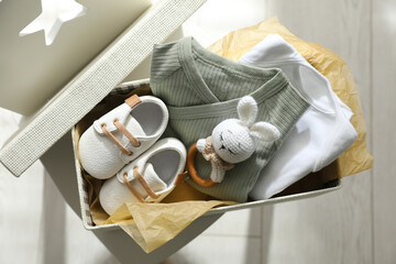 Wall Mural - Box with baby clothes, shoes and toy on chair indoors, top view