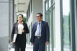 © DragonImages - Smiling senior businessman and businesswoman walking along the street of city downtown