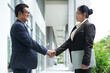 © DragonImages - Senior businessman and businesswoman looking at each other and shaking hands before negotiate a merger