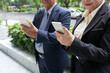 © DragonImages - Senior entrepreneurs standing on the street and checking text messages on smartphones