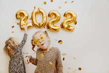 Two Little Girls Decorate The Wall Of The House With The Numbers 2022 With Foil Balls On Christmas Eve And New Year's Eve