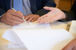 © DragonImages - Hands of female entrepreneur showing business partner where to sign contract