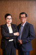 © DragonImages - Portrait of smiling confident senior businessman and businesswoman standing in office with arms crossed and looking at camera