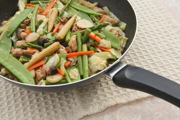 chinese teriyaki chicken and vegetable stir fry in wok on a table