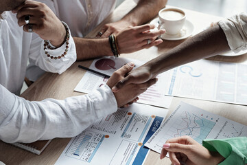 Wall Mural - Two successful Muslim businessmen shaking hands over financial documents by workplace