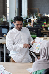 Aufkleber - Contemporary businessman with financial document looking at female colleague in hijab during discussion