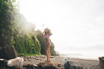 Wall Mural - Happy woman standing on rocky shore