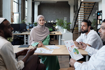 Poster - Group of young Muslim professionals discussing financial data at working meeting in office