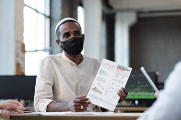 Aufkleber - Young Muslim businessman in protective mask looking at colleague during discussion