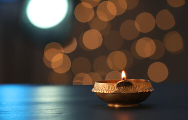 Wall Mural - Lit diya lamp on dark table, space for text. Diwali celebration