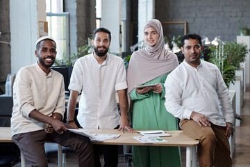 Aufkleber - Four young successful intercultural businesspeople standing by workplace in large office