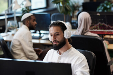 Aufkleber - Young man in headphones watching online video against his two colleagues interacting by workplace
