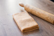 Side view of folded croissant dough, laminated dough and rolling pin on wooden table. lamination.