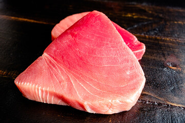 Wall Mural - Raw Tuna Steaks on a Dark Wood Background: Closeup view of uncooked tuna steaks on a wooden table