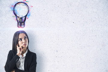 Poster - Portrait of attractive young european businesswoman with creative light bulb sketch on concrete wall background with mock up place. Idea and inspiration concept.