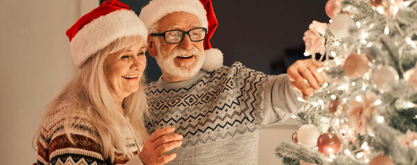 the happy old couple decorating the christmas tree