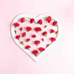 Canvas Print - A white heart-shaped frame filled with tiny red roses and buds. Minimal love concept on bright pink backgrounds