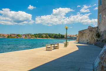 Poster - Part of the old defensive walls of the historic medieval coastal town of Porec in Istria, Croatia. The coast to the north of the town centre can be seen on the opposite shore
