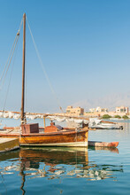 View To Traditional Fishing Boat In Harbour With Calm Water And Reflections Under Blue Sky In UAE