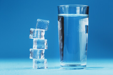 A glass of ice and clear water, ice cubes on a blue background.