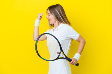 Young Romanian woman isolated on yellow background playing tennis and celebrating a victory