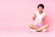 © luismolinero - Young Vietnamese woman with short hair sitting on the floor over isolated pink background celebrating a victory in winner position