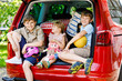 © Irina Schmidt - Three children, two boys and preschool girl sitting in car trunk before leaving for summer vacation with parents. Happy kids, siblings, brothers and sister with suitcases and toys going on journey