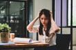 © Prathankarnpap - Stressed businesswoman looking at reports and holding her head.