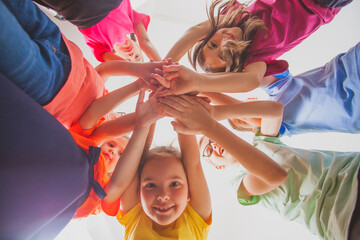 team of boys and girls are stacking hands together