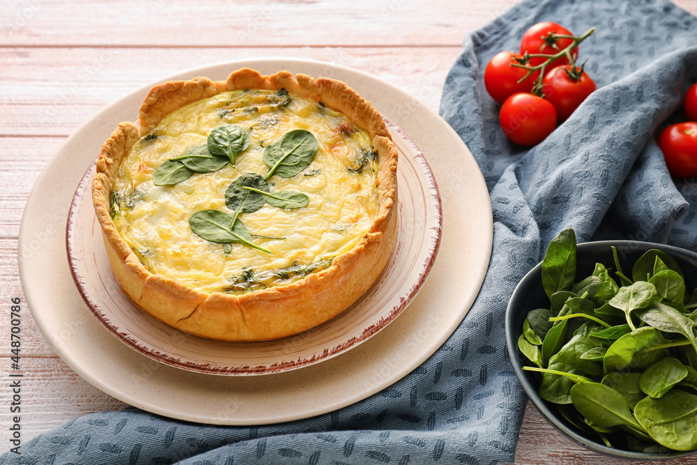 Tasty spinach tart and tomatoes on light wooden background