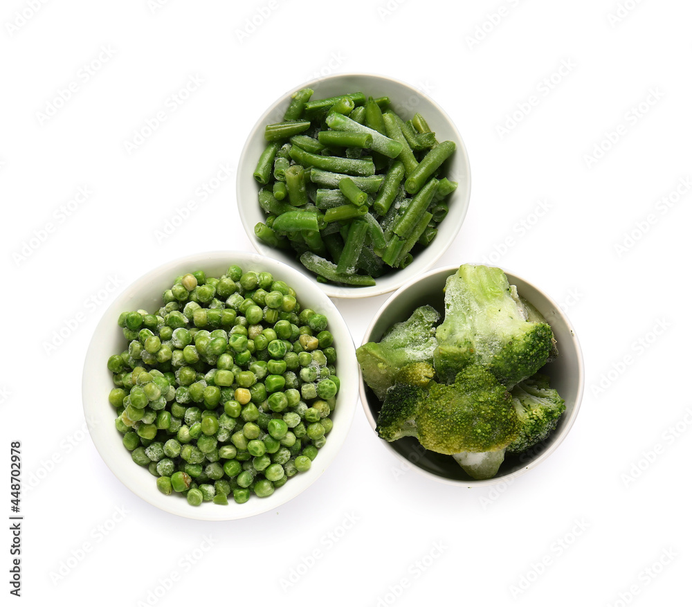 Bowls with frozen green vegetables on white background