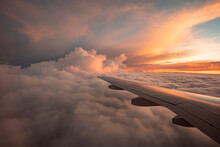 The View From The Airplane Window To The Clouds And Sunset. Airplane Wing Above Thick Pink And Orange Clouds. Wonderful Breathtaking View