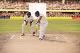 Fototapeta  - Cricketer batsman hitting a shot during a match on the pitch