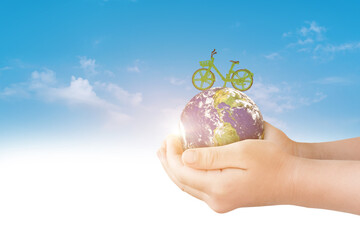 Hand holding globe earth with green bicycle on blue sky background. Environment day concept. Elements of this image furnished by NASA