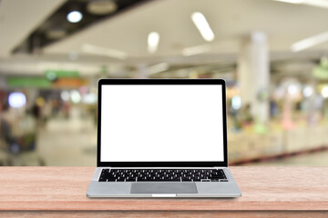 Wall Mural - laptop computer with blank screen on wood table over blur shopping mall background. mock up, templat