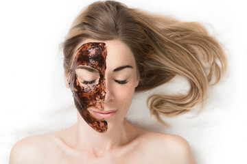 Facial Mask. Beautiful young woman relaxing in beauty spa salon, applying chocolate face mask