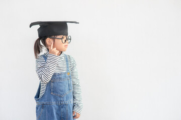 Happy Asian school kid graduate thinking with graduation cap