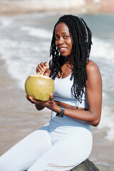 Wall Mural - Portrait of happy smiling fit woman drinking refreshing coconut cocktail after outdoor training on beach