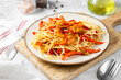 © Liudmila Zavialova - Pasta with eggplant, sweet pepper and carrots in a plate on a light gray table. Traditional Italian dish with vegetables close-up