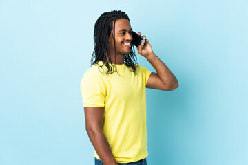 Wall Mural - Delivery African American man with braids isolated on white background keeping a conversation with the mobile phone