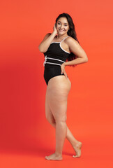 Wall Mural - Young beautiful plump woman in black underwear on orange background