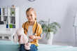 © LIGHTFIELD STUDIOS - Child holding toy, thermometer and stethoscope on medical couch