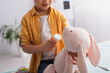 © LIGHTFIELD STUDIOS - Cropped view of kid holding pills near soft toy and blurred thermometer in clinic