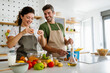 © NDABCREATIVITY - Young happy couple is enjoying and preparing healthy meal in their kitchen