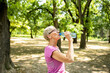 © littlewolf1989 - Elderly caucasian woman taking a break and drinking water after long running training in nature.