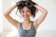 Young beautiful Asian girl smiles and plays with her hair. She is wearing a sporty top and red lipstick