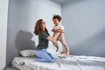 Wall Mural - Girl playing with her friendly mother while enjoying of the free time